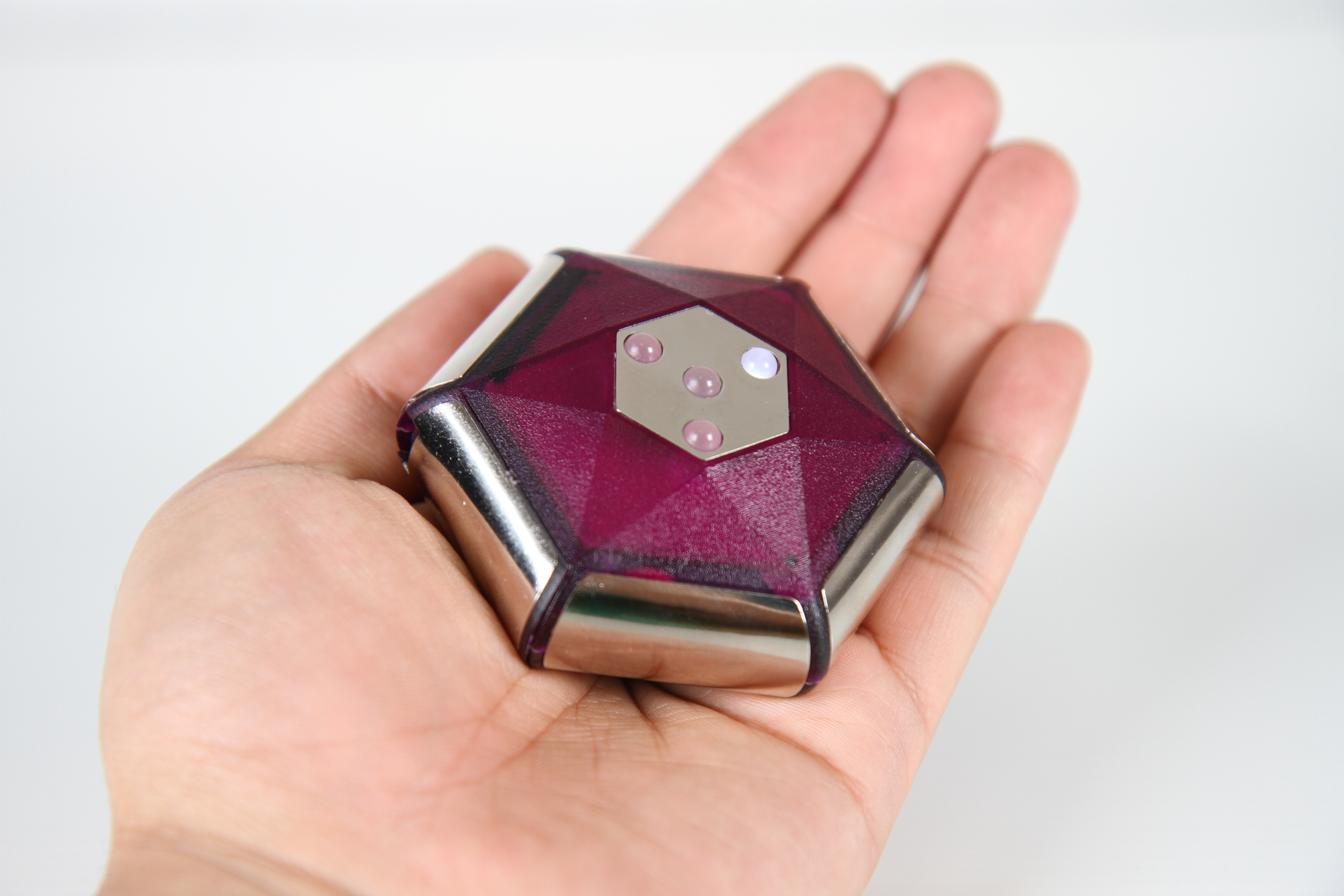 Photograph of Noumic device top view. Made from large metalic electro-sensors and purple plastic, four colour LEDs.